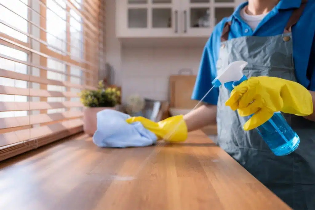 Woman spraying and wiping a wooden countertop